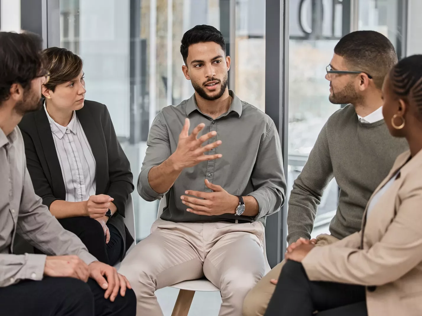 Man speaking to a group of other adults seated in chairs in a circle