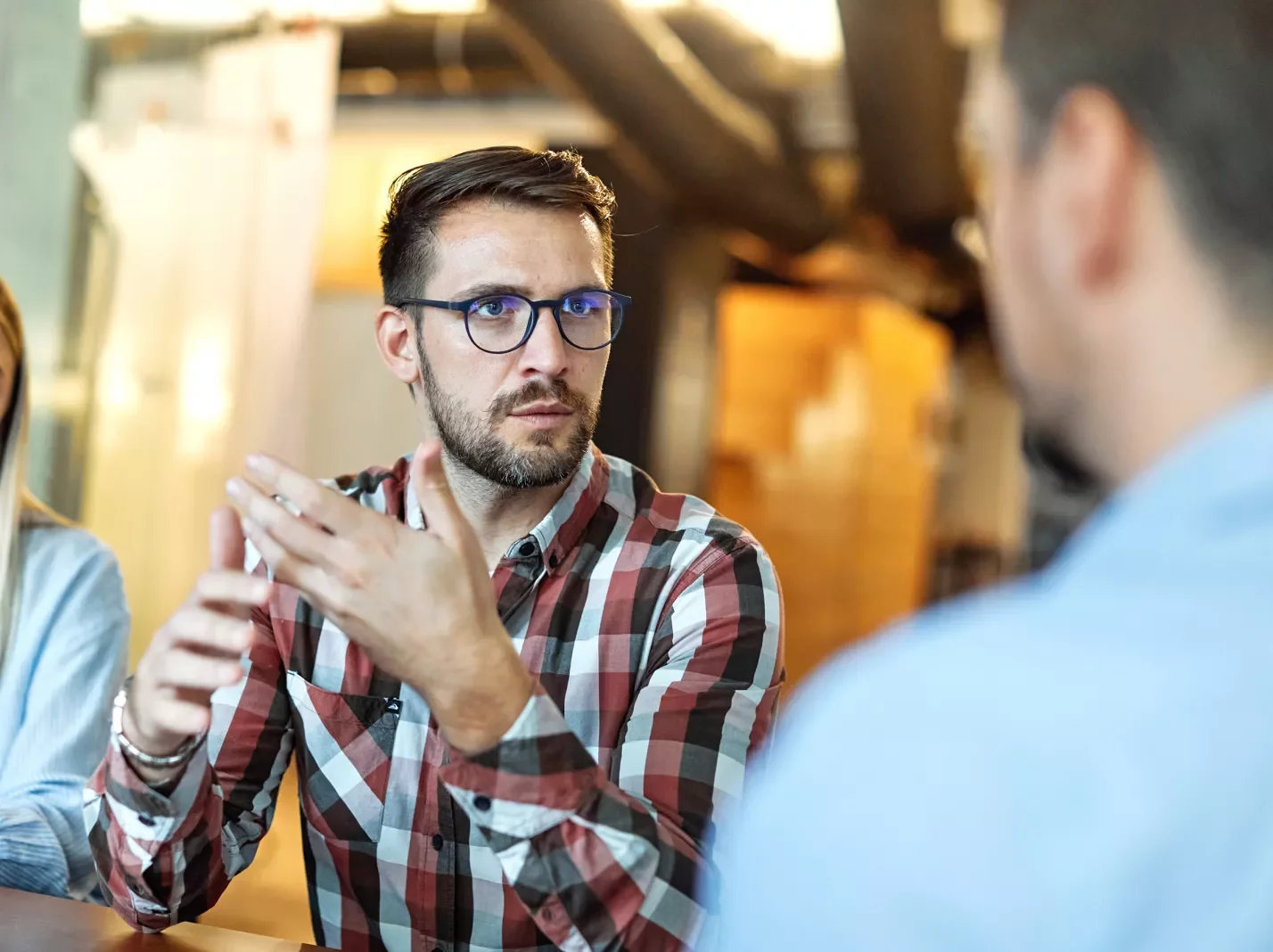 Man in a plaid shirt speaking with another man