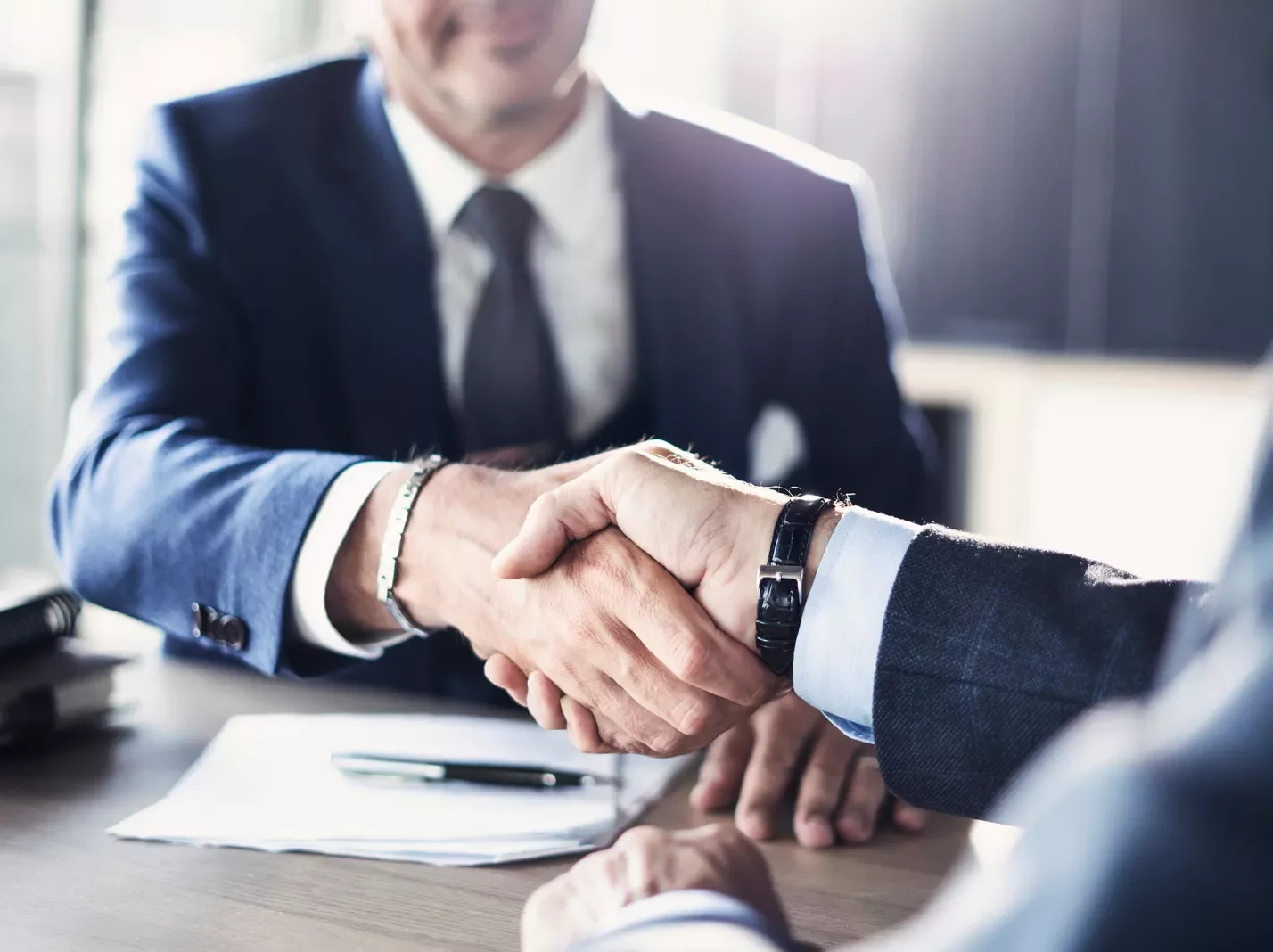 Businessmen shaking hands over a contract document