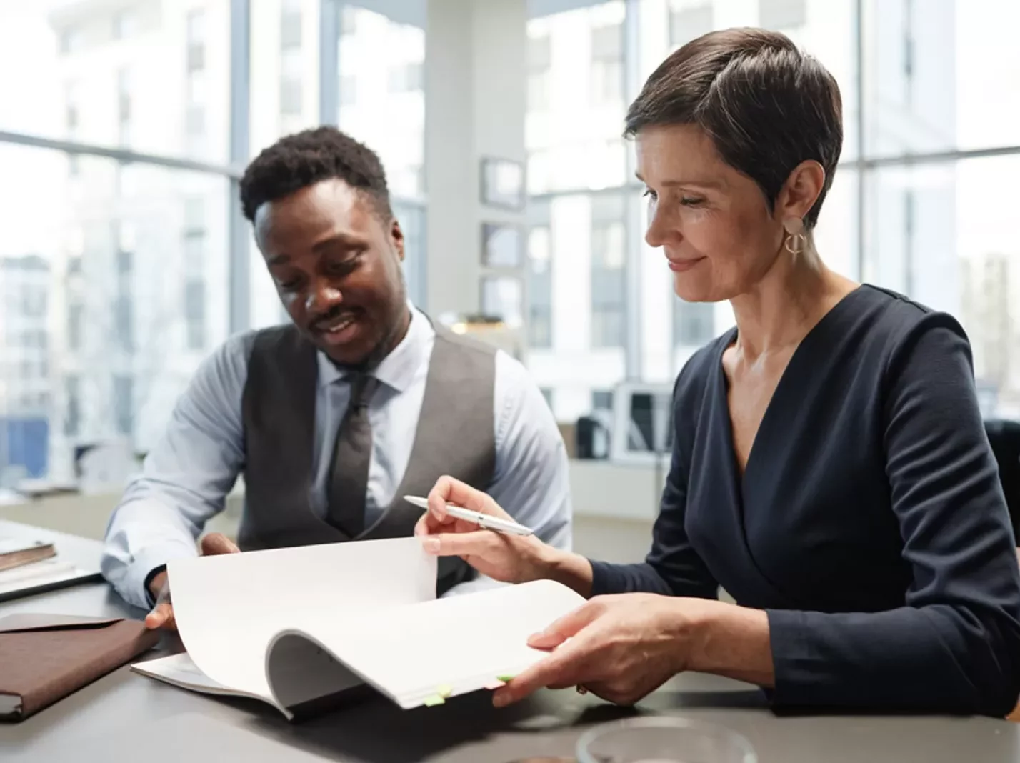 woman and man in business attire at a table reviewing paperwork