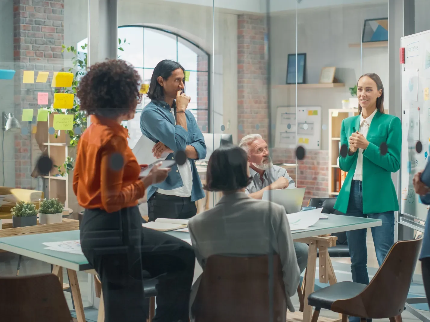 A group of people brainstorming around a table, some sitting, some standing