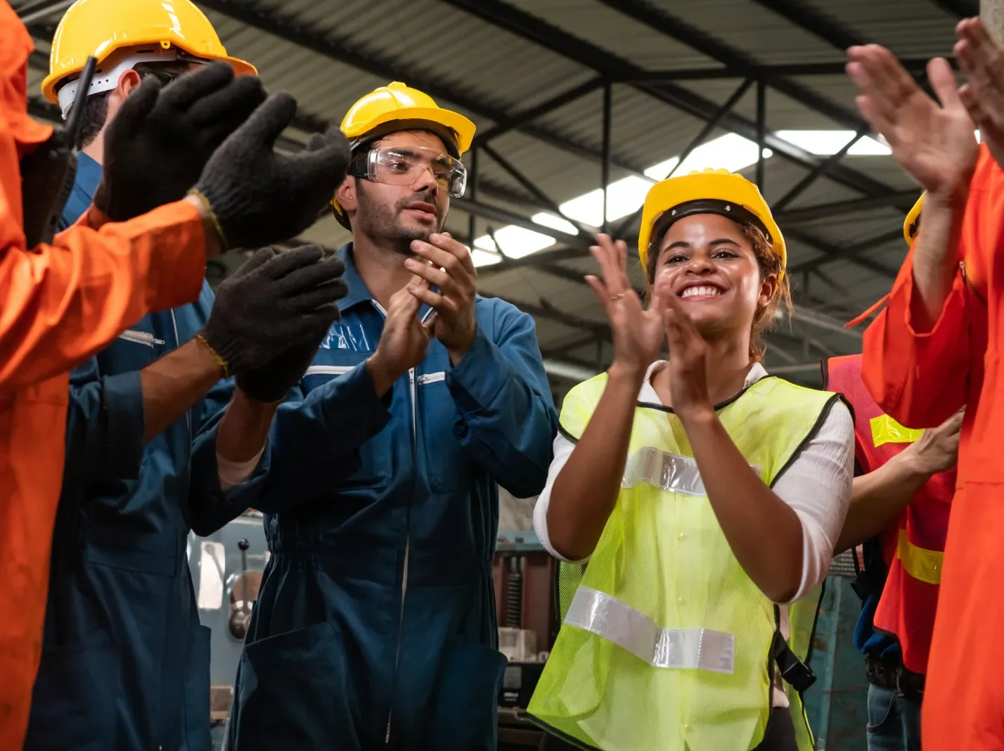 Workers in safety gear applauding in a warehouse
