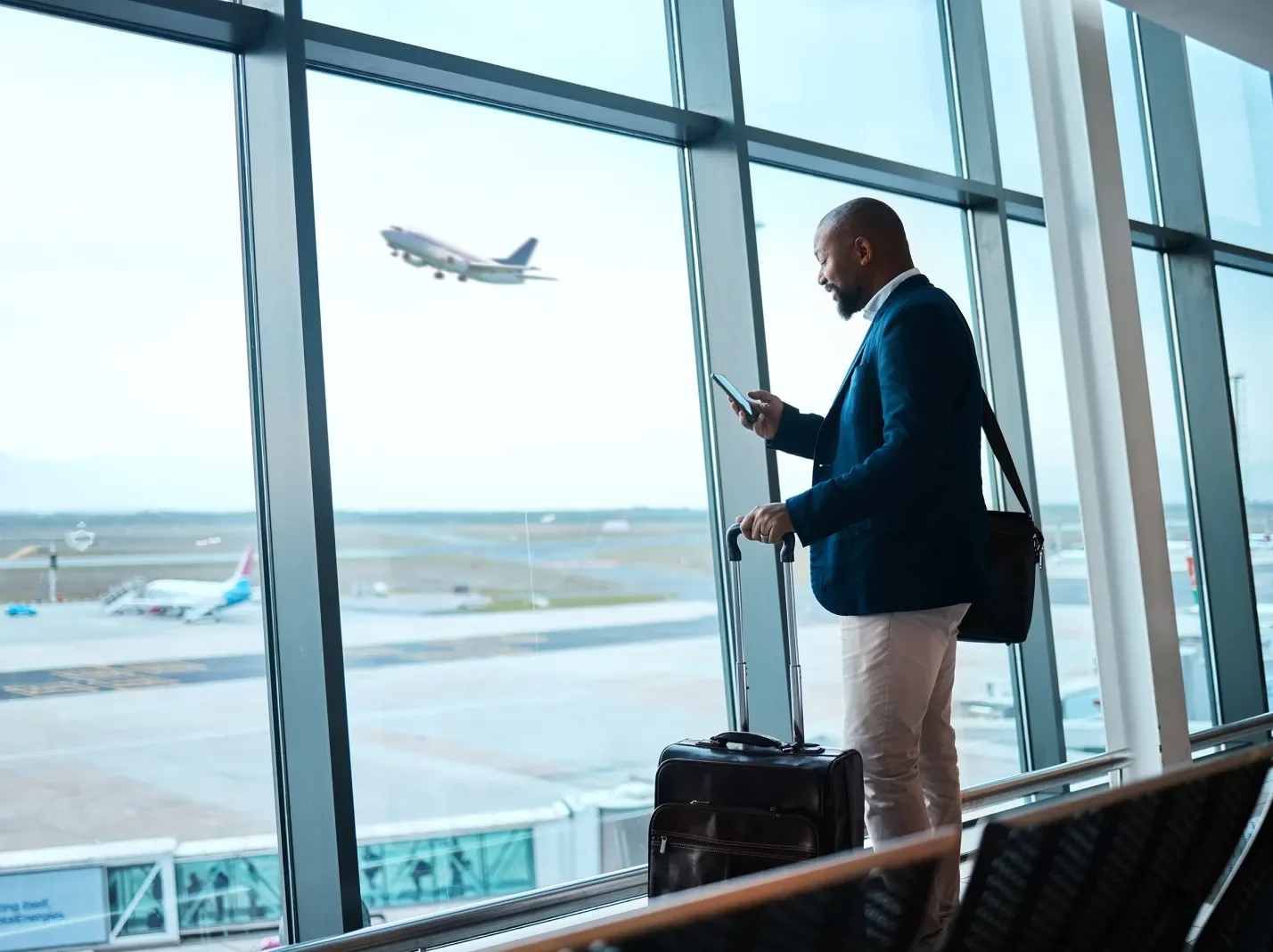 Transportation air travel man with luggage checking phone at airport