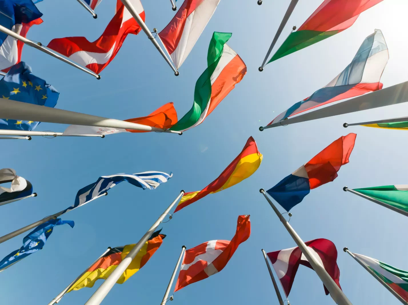 View looking up at a collection of world flags on flagpoles