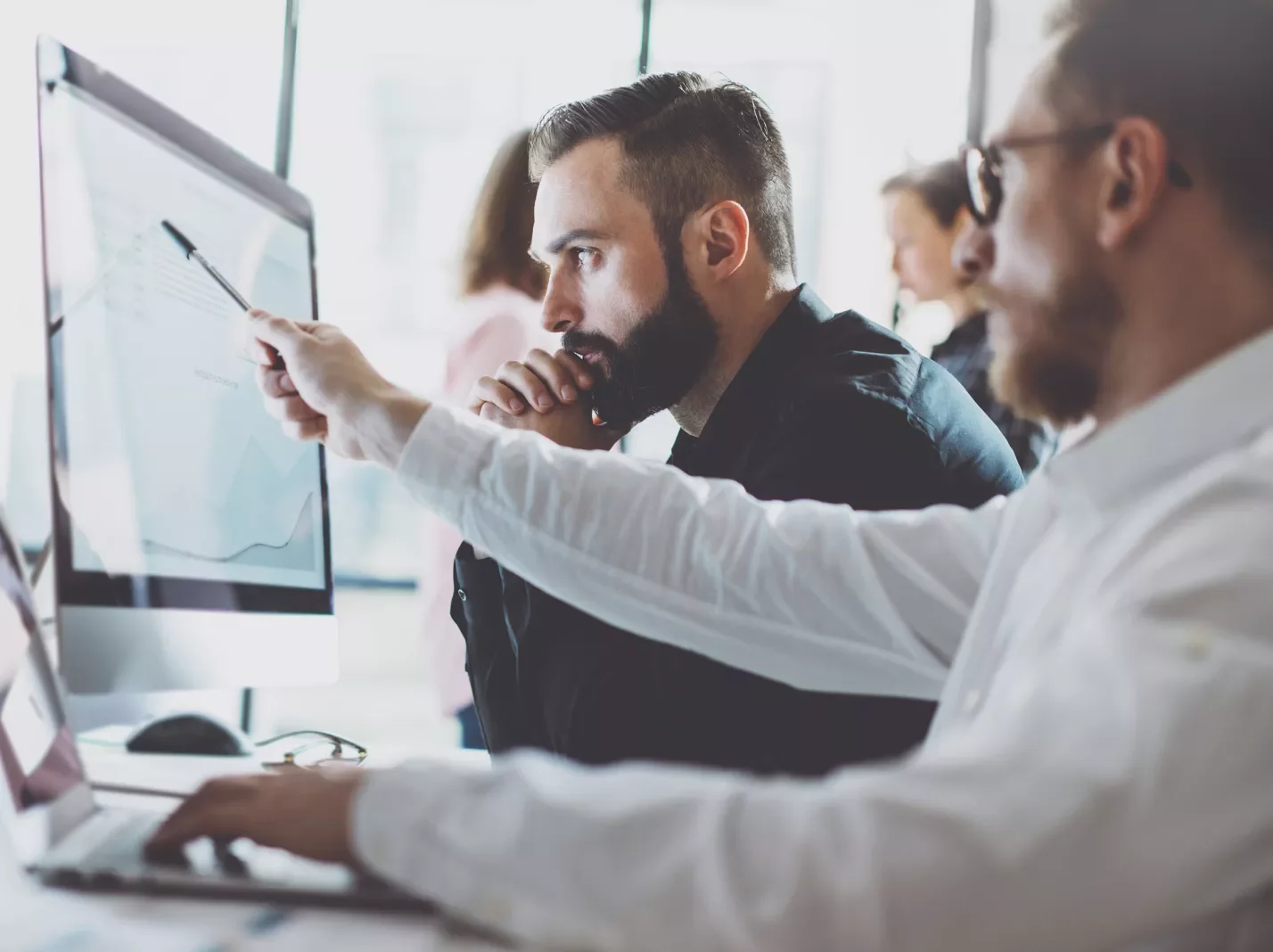 Men pointing at a graph on a computer screen