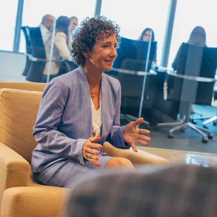 Woman in a suit sitting and talking outside a conference room