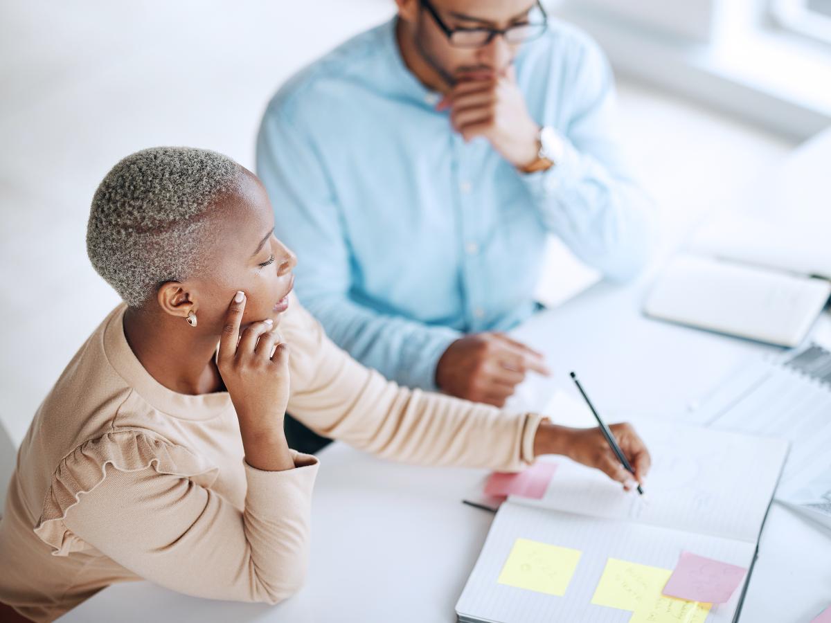 A woman and man are looking at a paper planner