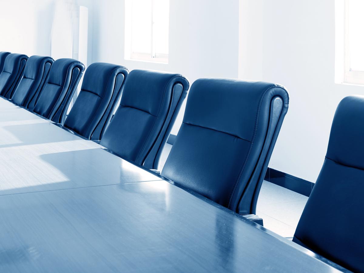A conference room table lined with empty chairs