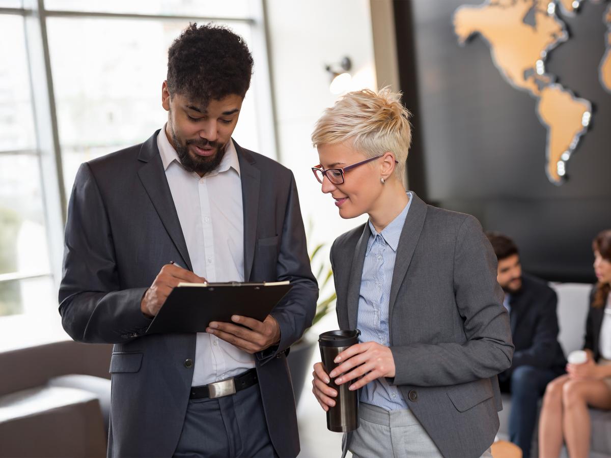 A man and woman talking with a world map in the background