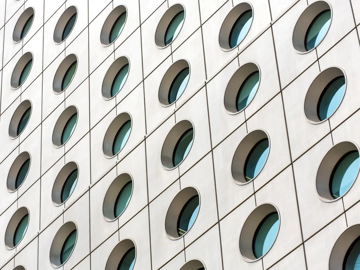 Looking up at the exterior of a concrete office building with round windows