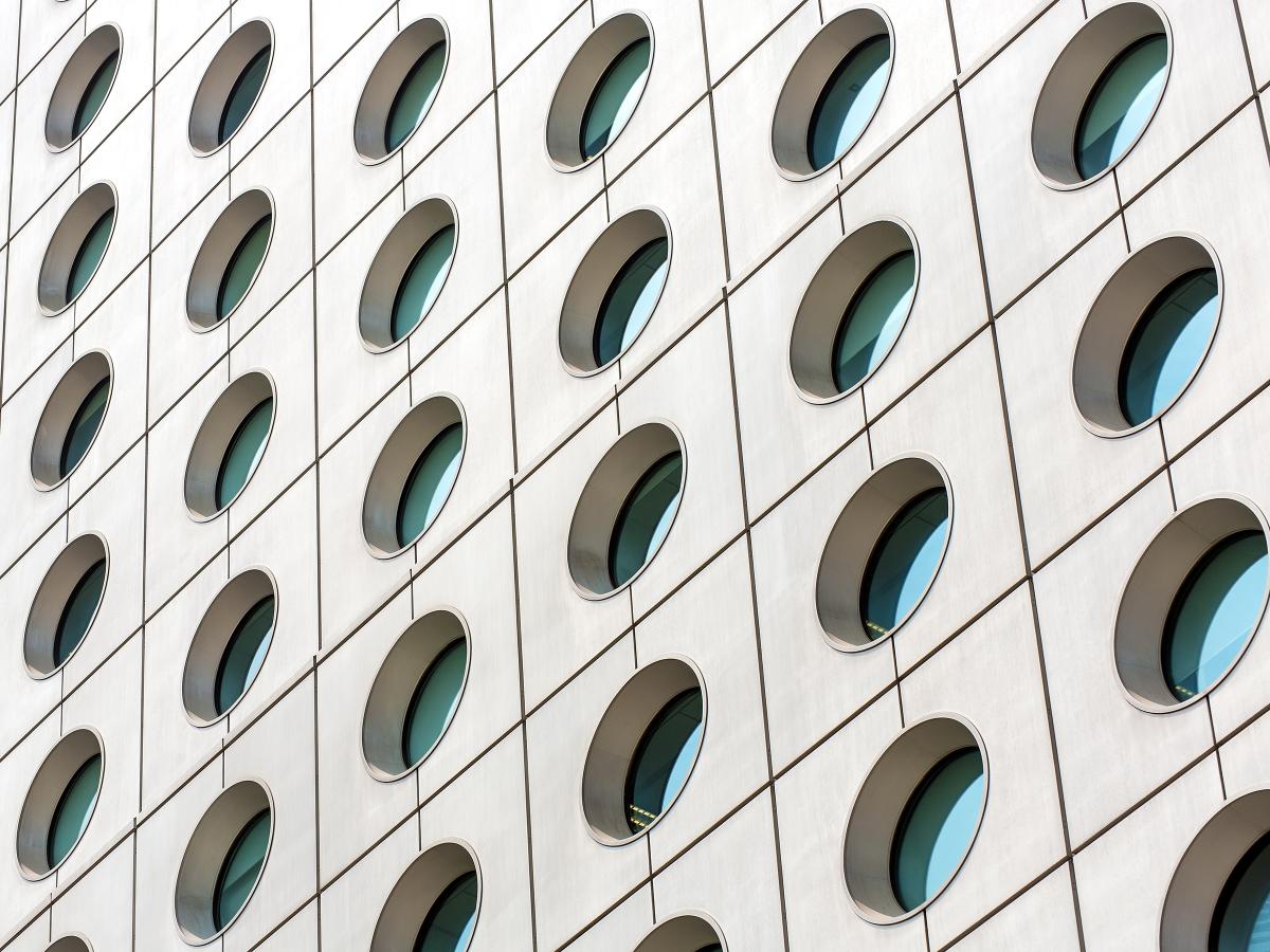 Looking up at the exterior of a concrete office building with round windows