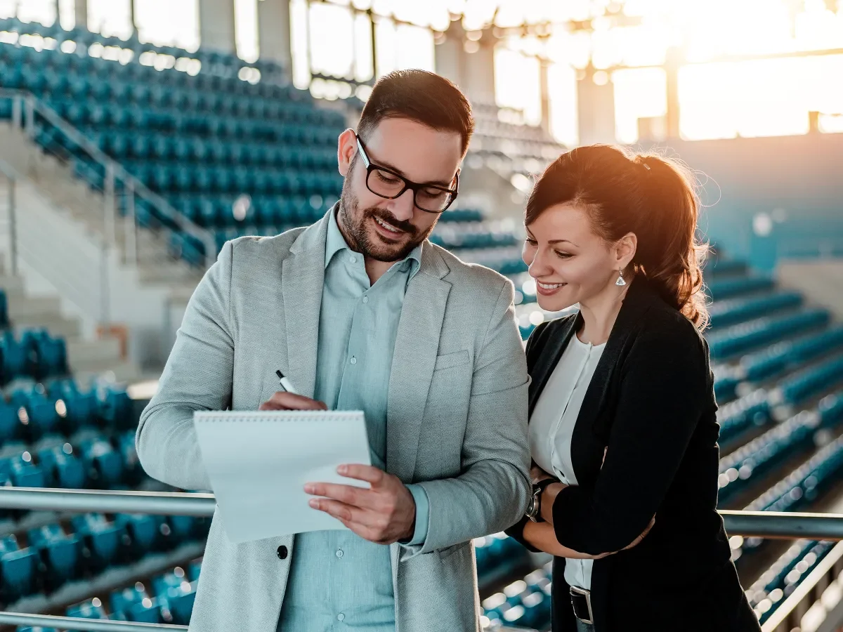 Man and woman in business attire standing in an empty stadium