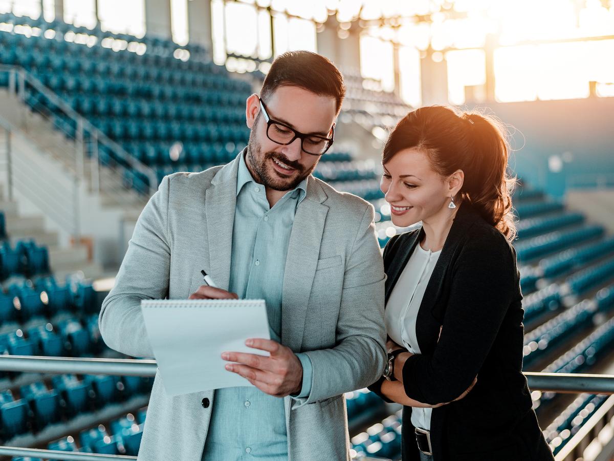 Man and woman in business attire standing in an empty stadium