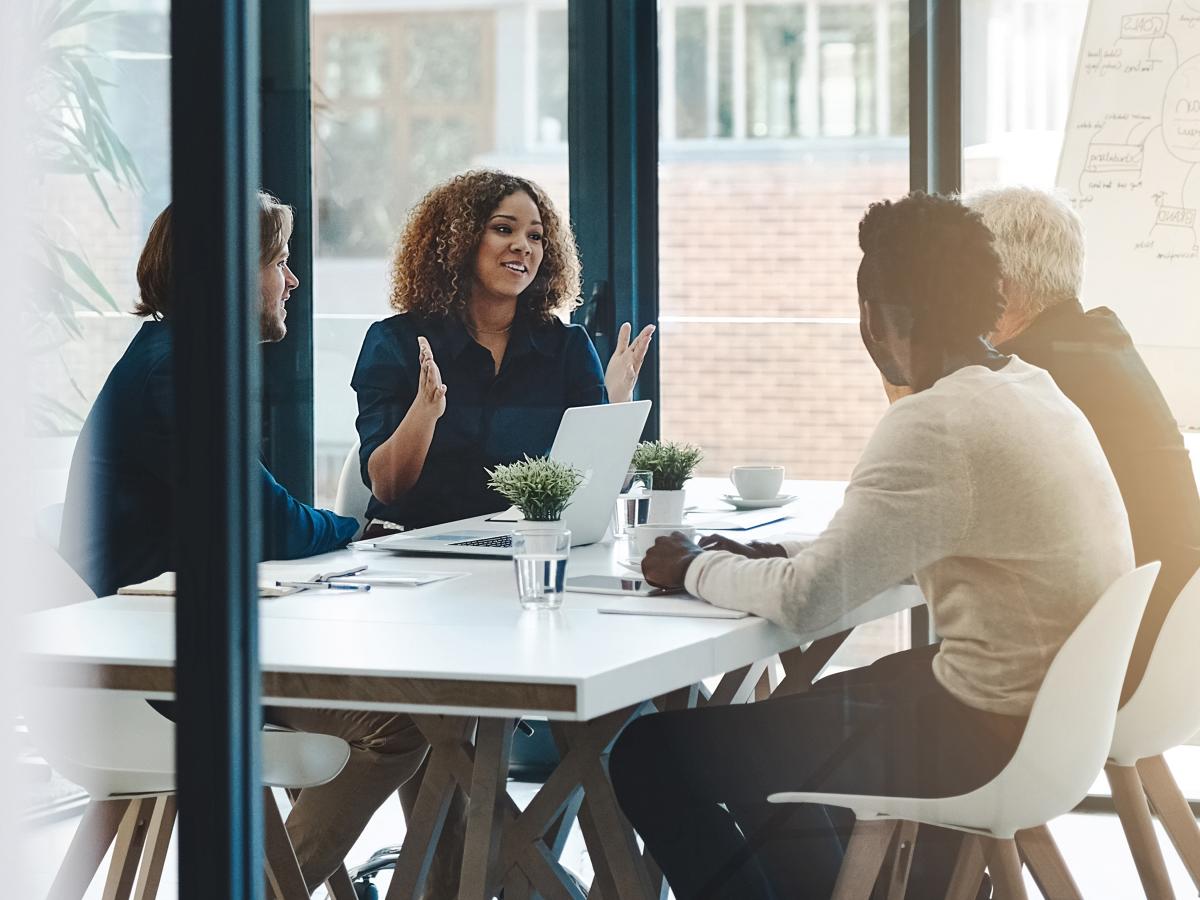 Group of people around a table in a glass office meeting room