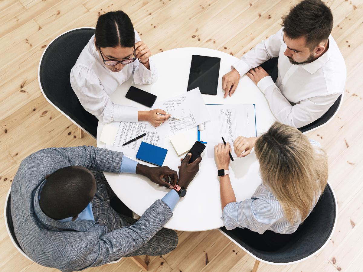 A view from above of four professionals sitting around a round table working