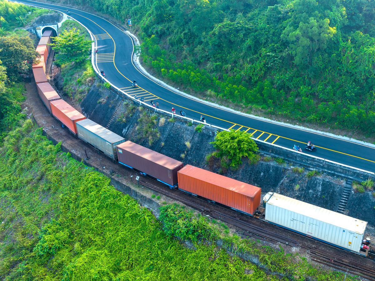 A train with container cars on the tracks next to a highway