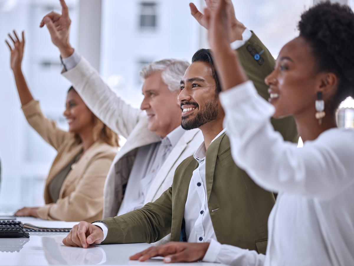 A group of professionals raising their hands in workplace training