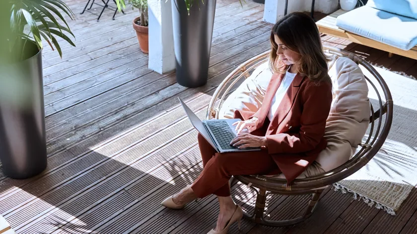 Overhead view of a woman in a suit sitting in a round chair holding a laptop