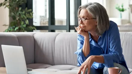 Woman on a couch watching a laptop screen
