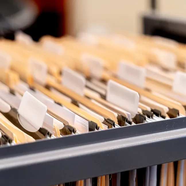 An open file cabinet drawer full of paper file folders